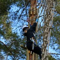 Tarzan-hypyn päätteeksi seikkailija nousee tasanteelle verkkoa pitkin − Seikkailupuisto Huippu